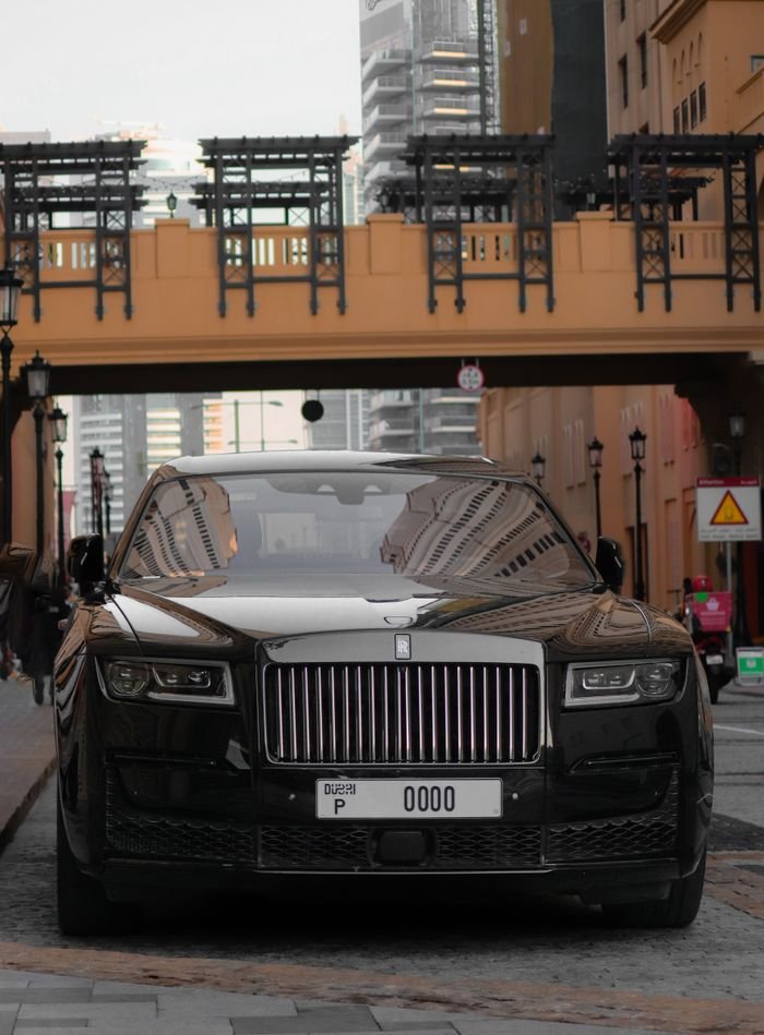 Front view of a Rolls-Royce parked in a modern cityscape, showcasing luxury and elegance.